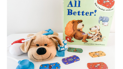 image of All Better! book standing up on a white table with a brown toy dog and bandaids